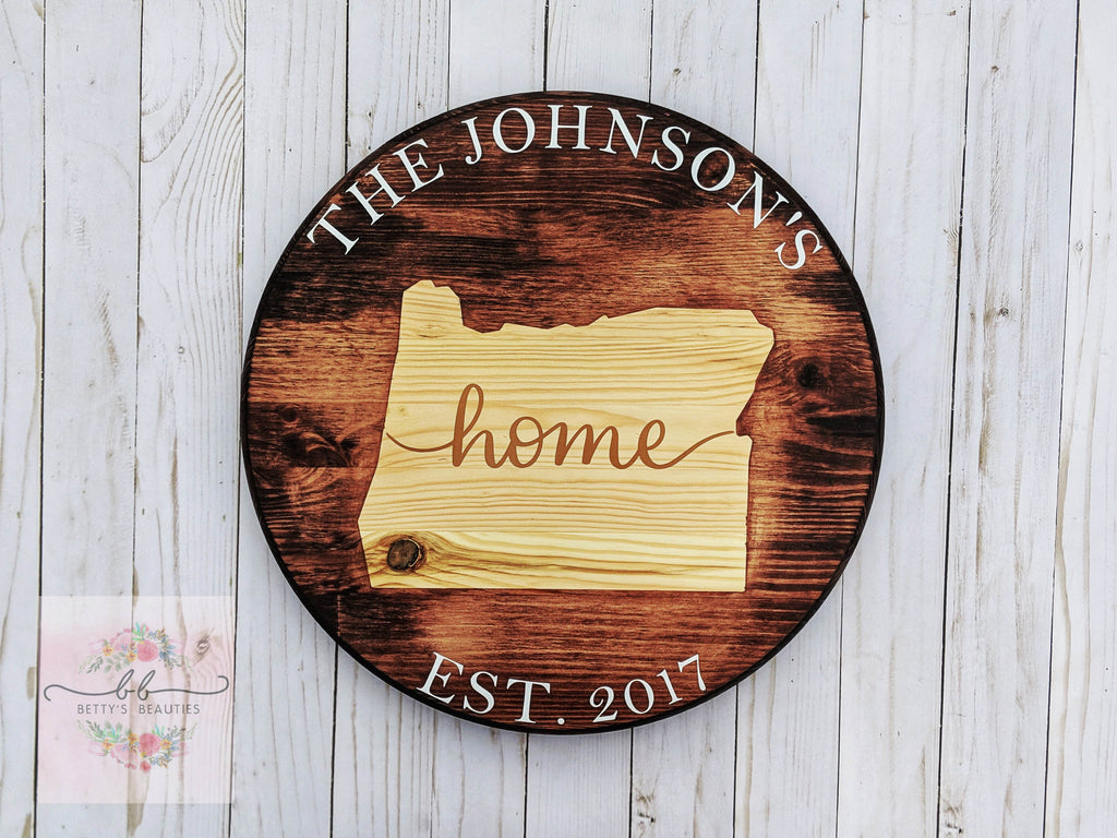 Home wood round with state outline and the word home written in a cursive font across it with family name and EST couple date 